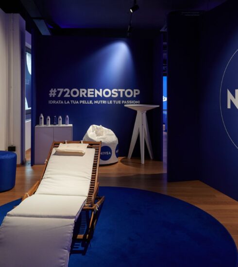 "Spazio relax NIVEA Body con lettino e decorazioni blu per l'evento #72ORENOSTOP, dedicato all'idratazione della pelle e al benessere personale."