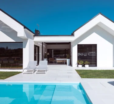 Scopri la villa minimal immersa nel verde con infissi Oknoplast: luce naturale, comfort e design senza barriere tra interno ed esterno.