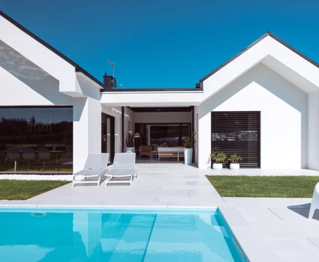 Scopri la villa minimal immersa nel verde con infissi Oknoplast: luce naturale, comfort e design senza barriere tra interno ed esterno.