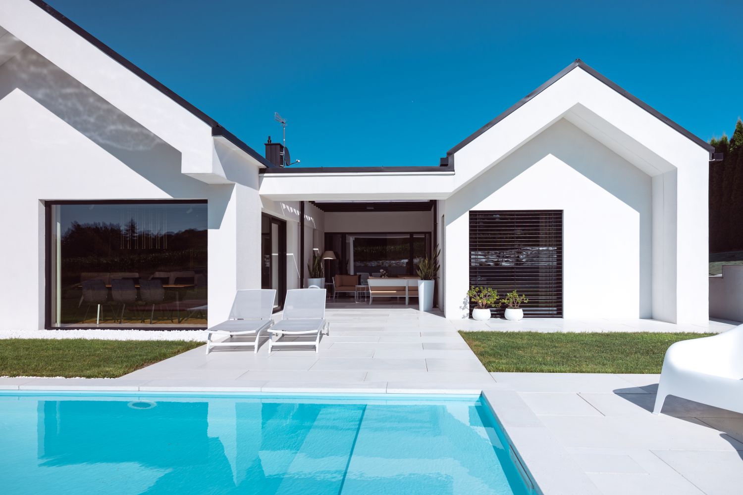 Scopri la villa minimal immersa nel verde con infissi Oknoplast: luce naturale, comfort e design senza barriere tra interno ed esterno.